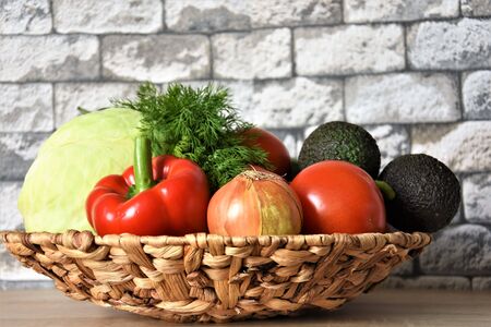 Fresh vegetables, white cabbage, red wig, tomatoes, avocado and onions in a wicker natural vase