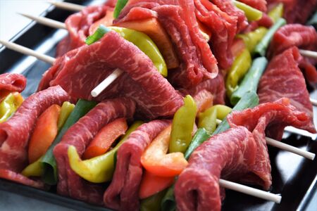 Fresh meat with pepperoni and paprika on a wooden stickの写真素材