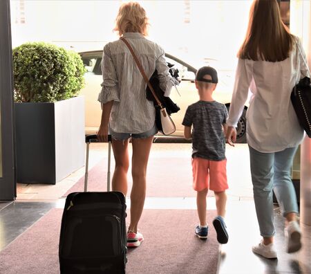 Two girls with a suitcase and a boy come out of the taxiの写真素材