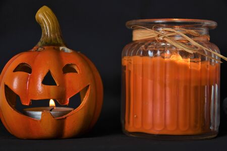 Pumpkin candlestick and candle on a glass jar on a black backgroundの写真素材
