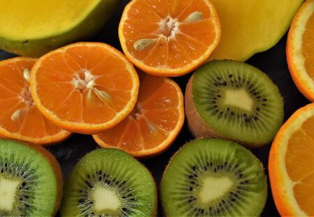 Halves of tropical fruits, clementines, orange, kiwi and mango