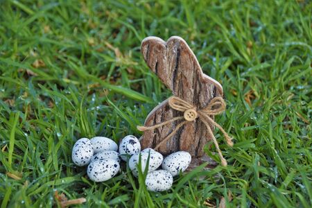 Easter bunny made of woody tree bark and quail eggs in green grass