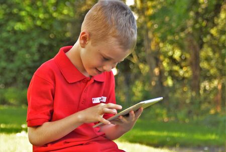 Short-haired boy holding a tablet in his hands