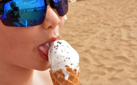 boy with mirrored glasses eating ice cream in a waffle coneの写真素材