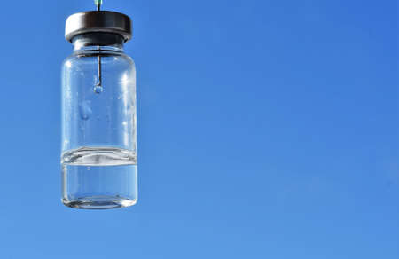 yringe with a needle in a vial of medicine on the background of the blue sky