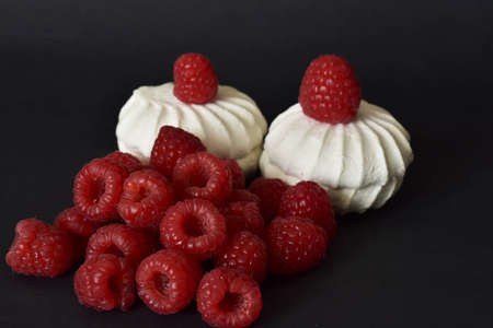 white marshmallows and fresh raspberries on black backgroundの写真素材