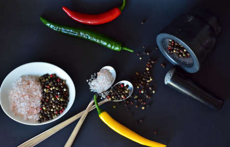 coarse salt and peppercorns, and chili pods on a black backgroundの写真素材