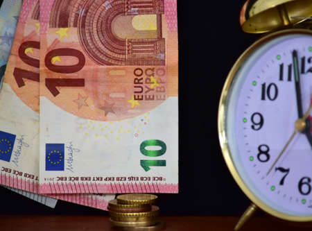 money and alarm clock on black background