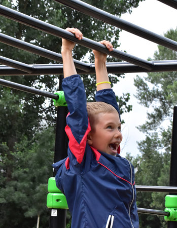 boy hanging on a horizontal bar outdoors