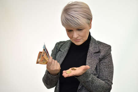 a woman with short blond hair holds euro bills and holds cents in her hand