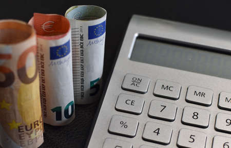 Calculator and euro banknotes on black background. Financial concept