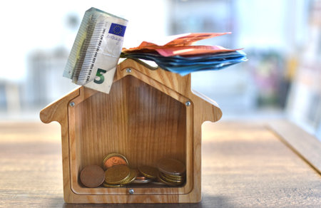 euro bills and coins in a wooden houset hrift boxの写真素材