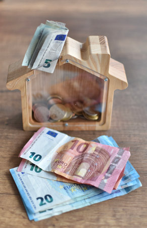 euro bills and coins in a wooden houset hrift boxの写真素材