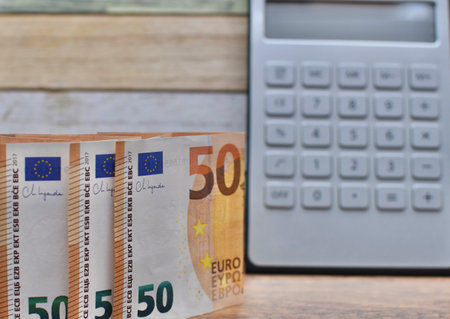 calculator and euro banknotes on a wooden table, business concept