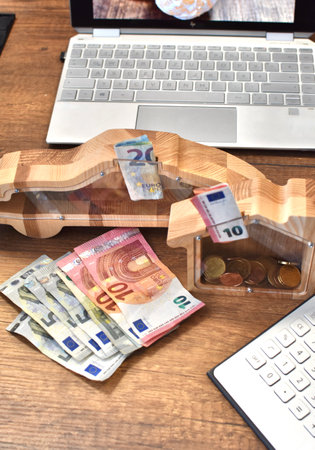 wooden piggy banks with money and calculator with laptopの写真素材