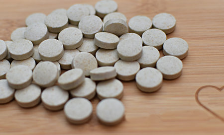 Heap of white pills on wooden background. Focus on foreground.の写真素材