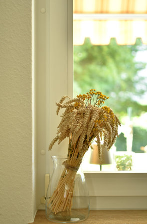 Bouquet of dry ears of wheat and wild wormwood flowers in a glass vaseの写真素材