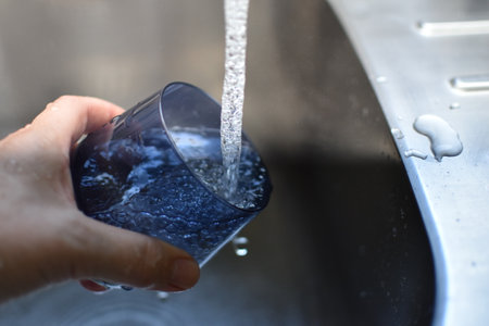 water pours from a tap into a glassの写真素材