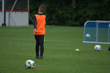Boy in an orange T-shirt on a football fieldの写真素材
