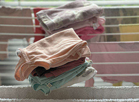 a pile of washed dried clothes stacked on the dryerの写真素材