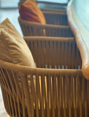 wicker chair with cushion near wooden tableの写真素材