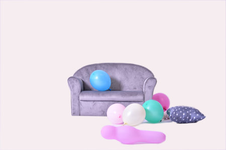Small gray sofa with colorful balloons and decorative pillows on white backgroundの写真素材