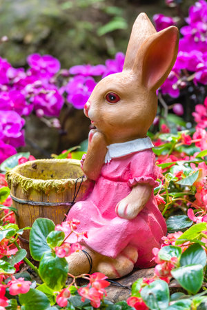Rabbit doll in the garden with pink flowers, selective focus.の写真素材