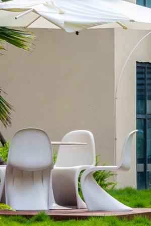 Outdoor patio with white plastic chair and umbrella in hotel resort.の写真素材