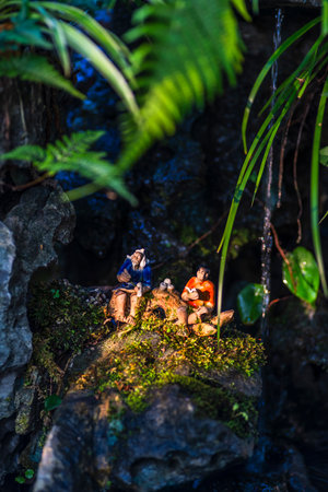 Miniature people : Couple sitting on the rock in the forestの写真素材