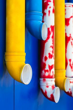 Yellow and red plastic pipes on a blue wall, close-upの写真素材