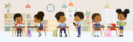 Dark skin children studying at multiracial elementary school sitting at tables talking together at classroom vector flat illustration. Diverse schoolboy and schoolgirl classmates wearing uniformのイラスト素材