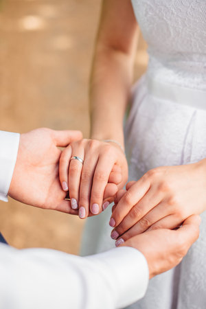 the hands of the newlyweds with rings hold each otherの写真素材