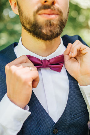 the groom adjusts the red bow tie on the suitの写真素材