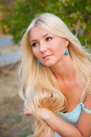 lovely beautiful blonde woman against sunny outdoor greeneryの写真素材