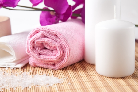 pink towel and two candles on wooden surface with purple flower on a backgroundの写真素材