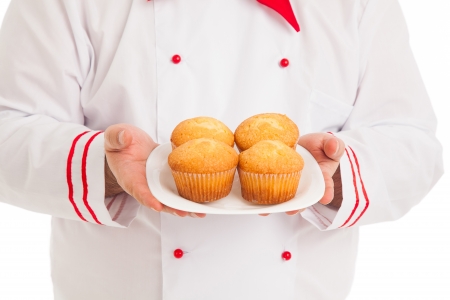 chef holding plate with 4 muffins wearing red and white uniform over white background の写真素材