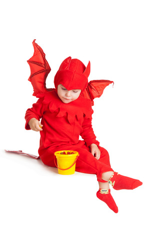 little boy in red devil costume sitting with bucket over white backgroundの写真素材