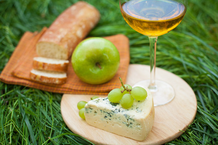 still life with white wine, baguette, cheese, grape and apple on the grass の写真素材