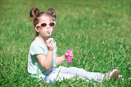 child girl blowing soap bubbles outdoorの写真素材