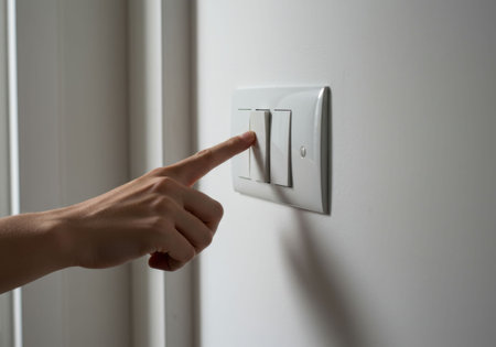 Woman turning light switch on wall. Concept of saving energy and everyday household routine. Simple action controlling electricity at home.の素材
