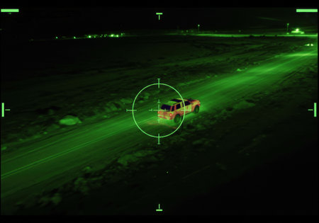 Thermal night vision view of car on remote road. Military drone target system. Modern armed forces operation. Aerial surveillance.の素材