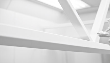 Builder painter spraying white paint onto metal construction. Craftsman using airbrush for industrial painting work. Factory maintenance concept.の素材