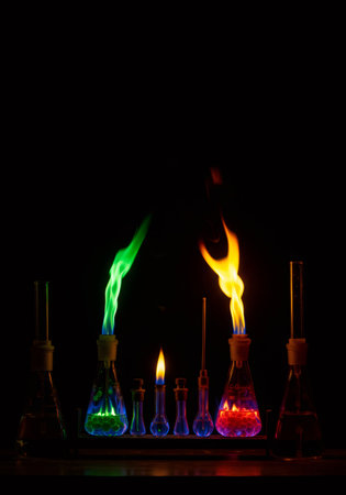 Colorful flames burning from various chemical flasks on a dark background showcasing chemical reactions and elements concept for science.の素材