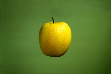 Yellow apple on a green background.の写真素材