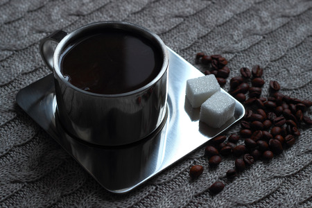 black morning coffee in a metal Cup on the metal plate with coffee beans and sugar cubesの写真素材