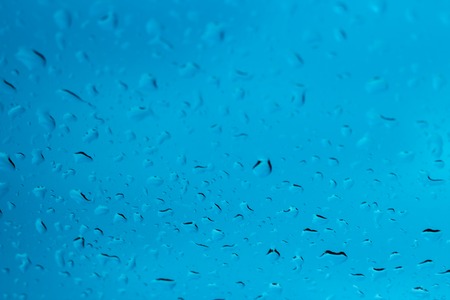 Raindrops on glass on a blue backgroundの写真素材