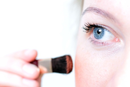 a woman using red powder on her face
