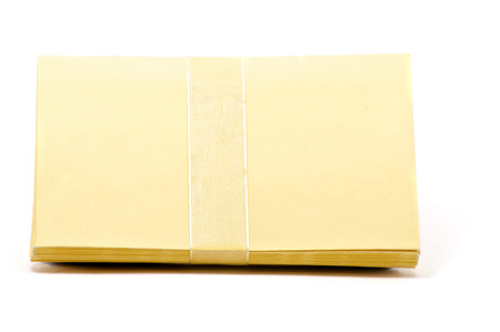 Stack of yellow greeting cards with ribbon over whiteの写真素材