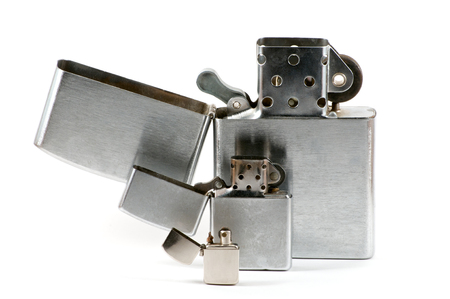 Three different sizes of metallic lighters with cap closed over whiteの写真素材