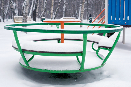 Children green round swing in snow during winter in Russiaの写真素材